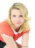 Annette Frier sitzt vor weißem Hintergrund und schaut direkt in die Kamera. Sie hat blond gefärbte schulterlange gelockete Haare und blaue Augen. Sie trägt eine orange Bluse mit weißem Kragen und einen schwarzen Rock.&nbsp;&copy;&nbsp;Roland Breitschuh