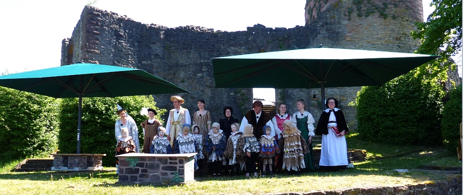 Jeden dritten Sonntag ab Mai bis September findet das Aschenputtelspiel auf der Poller Burg statt.
Auf dem Bild sind die ganzen Schauspieler des Theaterstückes zu sehen, alle sind Bunt in ihren Kostümen verkleidet. Von kleinen Kindern, die als Tauben verkleidet sind bis zum Aschenputtel sind alle dabei.
Die Schauspieler stehen auf dem Rasen unter zwei großen Sonnenschirmen.
Im Hintergrund ist die Burgruine zu erkennen.&nbsp;&copy;&nbsp;Laienspielgruppe Polle e.V.