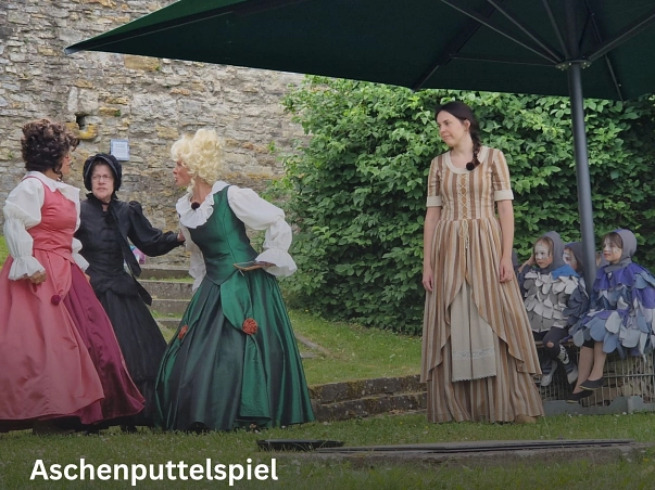 Jeden dritten Sonntag ab Mai bis September findet das Aschenputtelspiel auf der Poller Burg statt.
Auf dem Bild sind die ganzen Schauspieler des Theaterstückes zu sehen, alle sind Bunt in ihren Kostümen verkleidet. Von kleinen Kindern, die als Tauben verkleidet sind bis zum Aschenputtel sind alle dabei.
Die Schauspieler stehen auf dem Rasen unter zwei großen Sonnenschirmen.
Im Hintergrund ist die Burgruine zu erkennen.&nbsp;&copy;&nbsp;Laienspielgruppe Polle e.V.
