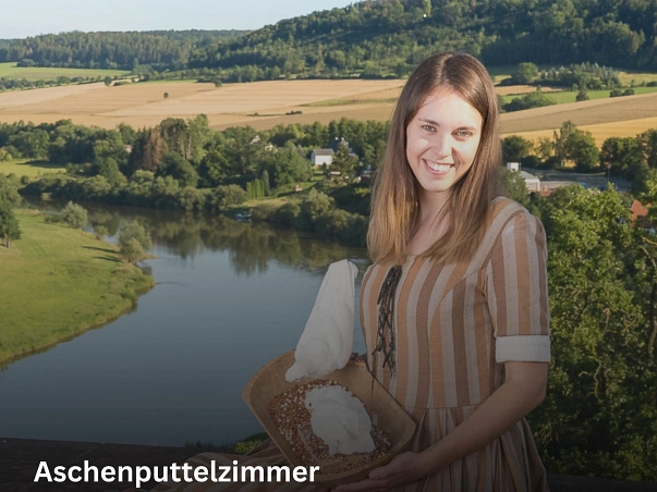 Zu sehen ist die Darstellerin des Aschenputtels. Sie sitzt oben auf der Burgruine, sodass im Hintergrund ein Teil des Ortes Polle, umgeben von grünen Bäumen, und auf der linken Seite die Weser zu sehen ist. Sie lächelt in die Kamera und trägt ein in verschiedenen Brauntönen gestreiftes Kleid. Auf dem Schoß steht eine Molle mit diversen Körnern und zwei weißen Tauben darin.&nbsp;&copy;&nbsp;Laienspielgruppe Polle e.V.