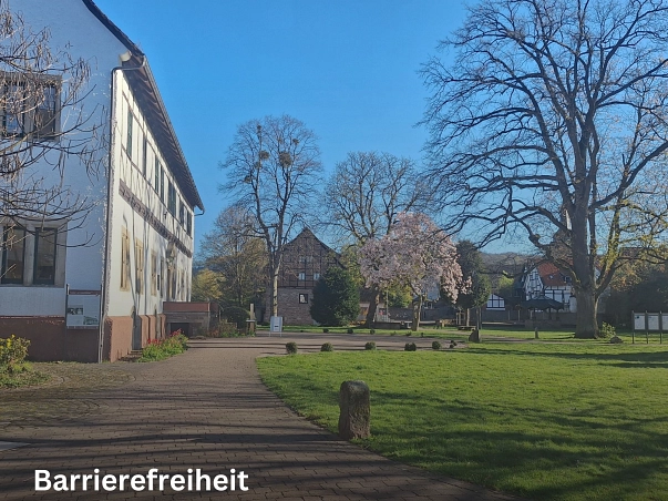 Barrierefreiheit.jpg Zu sehen ist der Blick in den Rathauspark Bodenwerder aus Sicht des Brennereihauses. Link ist ein großes weißes Fachwerkgebäude zu sehen. Das Geburtshaus des Baron von Münchhausen und heutige Rathaus. Rechts davon ist im Hintergrund das Münchhausen-Museum, ein rotes Fachwerkgebäude zu sehen. Auf der rechten Seite ist eine Rasenfläche, dahinter stehen einige Bäume. © Samtgemeinde Bodenwerder-Polle