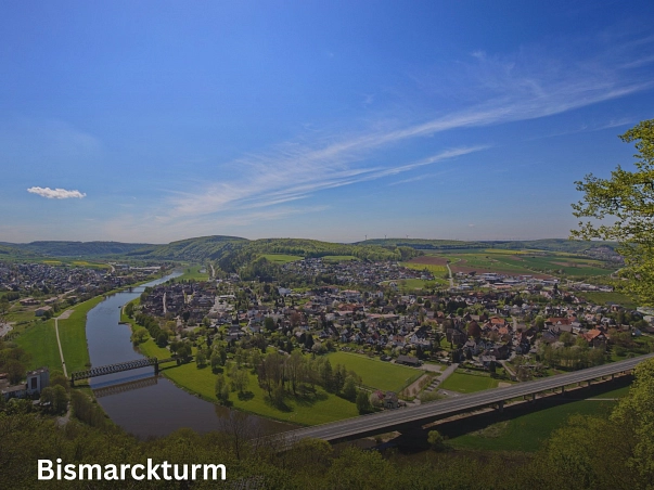 Bismarckturm.jpg Zu sehen ist der Ausblick vom Bismarckturm auf Bodenwerder. In der linken Hälfte sind die Weser sowie das Wohngebiet auf der Ostuferseite zu sehen. Außerdem die altre Eisenbahnbrücke über die Weser. Rechts ist die Altstadt Bodenwerders sowie die darum liegenden Wohngebiete zu sehen. Im oberen teil des Bildes ist ein strahlend blauer Himmel. © Samtgemeinde Bodenwerder-Polle/LeoDesign