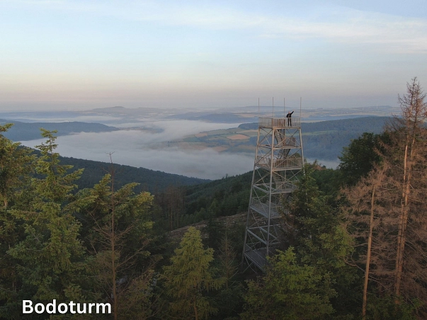 Bodoturm.jpg Auf dem Bild ist eine Luftaufnahme des Bodoturmes zu sehen. Im Hintergrund schlängelt sich ein mit Nebel bedecktes Tal zwischen den Gebirgszügen durch. Oben auf dem Stahlturm ist eine Person zu sehen, die winkt. © SVR/M. Sprödefeld