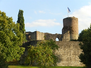 Auf dem Bild ist die Burgruine mit ihrem Bergfried in Polle zu sehen. Ganz oben auf dem Bergfried ist die Poller Flagge gehisst, welche weiß-blau ist und das Wappen mit einer Burg und einem Löwen zeigt. Vor den Mauern der Burg und auf der Oberburg wachsen Bäume.&nbsp;&copy;&nbsp;Samtgemeinde Bodenwerder-Polle-Andreas Busche