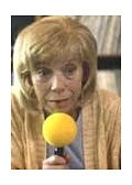 Evelyn Hamann blickt fokussiert nach unten und hat ein gelbes rundes Mikrofon in der rechten Hand. Sie hat blonde Haare und trägt eine gelbe Strickjacke.&nbsp;&copy;&nbsp;Münchhausenstadt Bodenwerder