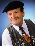 Günter Willumeit blickt vor blauem Hintergrund in die Kamera. Er hat einen Schnäuzer und hat eine schwarze Baskenmütze auf. Er trägt eine dunkelgraue Weste mit zahlreichen Ansteckern und eine dunkle Krawatte über weißem Hemd.&nbsp;&copy;&nbsp;Foto Bericht: Thorsten Sienk
Fotos Bildergalerie: Jens Bremeyer