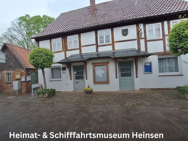 Heimat- & Schiffahrtsmuseum Heinsen.jpg Zu sehen ist das Gebäude des Heimat- & Schifffahrtsmuseum sowie der Gemeinde in Heinsen. Dies ist ein weißes Fachwerkgebäude. Links und rechts stehen je ein Baum. DAS Gebäude hat zwei Eingangstüren. Beide sind in einem hellen Grün und haben ein Vordach darüber. Zwischen den beiden Türen hängt ein Aushangkasten mit einem Holzrahmen. Links neben dem Gebäude ist noch ein kleines Backsteingebäude zu sehen. © Samtgemeinde Bodenwerder-Polle
