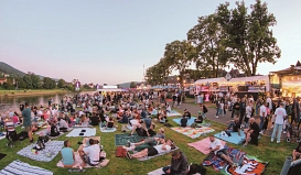 Das Bild zeigt die Weserpromenade in Bodenwerder am Tag des Lichterfestes 2025. Hier zu sehen sind auf der rechten Seite sowie bis in den Hintergrund verschiedene Verpflegungsstände, links ist die Weser zu sehen. Auf der Rasenfläche sitzen und liegen viele Menschen auf Decken oder auf dem Rasen. Auf dem Weg rechts sind ebenfalls viele Menschen zu Fuuß unterwegs.
