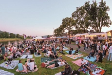 Lichterfest Bodenwerder 2025 Das Bild zeigt die Weserpromenade in Bodenwerder am Tag des Lichterfestes 2025. Hier zu sehen sind auf der rechten Seite sowie bis in den Hintergrund verschiedene Verpflegungsstände, links ist die Weser zu sehen. Auf der Rasenfläche sitzen und liegen viele Menschen auf Decken oder auf dem Rasen. Auf dem Weg rechts sind ebenfalls viele Menschen zu Fuuß unterwegs.