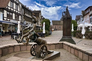 Der große Münchhausen- Brunnen in der Fußgängerzone in Bodenwerder wurde 1994 von Bonifatius Stirnberg aus Aachen erschaffen. 
Dieser Brunnen zeigt drei der bekanntesten Münchhausengeschichten mit dem Pferd am Kirchturm, der Entenflug sowie der Ritt auf der Kanonenkugel. 
Das Pferd am Kirchturm erzählt über die Geschichte als sich der Baron von Münchhausen auf dem Weg nach Russland im tiefsten Winter mit seinem Pferd zum Schlafen niederließ. Als er am nächsten Tag erwachte hing das Pferd mitten auf dem Kirchplatz am Kirchturm. 
Beim Entenflug ging es darum, dass der Baron Enten schießen wollte am See. Durch einen raffinierten Trick hatte er alle Enten an einer Leine, so dass keine wegfliegen konnte. Er wollte sie mit nach Hause nehmen, doch auf dem Weg dahin flogen sie mitsamt Münchhausen wieder Richtung See. 
Der Ritt auf der Kanonenkugel handelt davon, dass ein Marschall im Feldzug wissen wollte wie es in einer Festung aussah. Deshalb stellte sich Münchhausen neben eine Kanone und wartete bis die nächste Kugel heraus kam um auf sie zu springen. Somit flog er mit der Kanonenkugel in die Festung.
Von dem Münchhausen- Brunnen aus hat ist im Hintergrund die Sicht auf die St. Nicolai Kirche gegeben.&nbsp;&copy;&nbsp;Samtgemeinde Bodenwerder-Polle - Rolf Sander