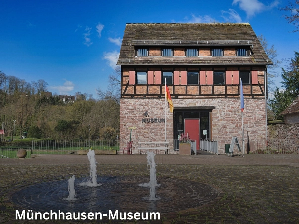 Münchhausen-Museum.jpg Das Museum in Bodenwerder befindet sich östlich des Rathauses und es führt ein direkter Weg dorthin. Unmittelbar vor dem Eingang befindet sich ein vierstrahliger Brunnen der umgeben von Pflastersteinen ist.
Es ist ein dreistöckiges historisches Gebäude in dem sich in der obersten Etage eine Sonderausstellung zum Baron befindet. In der ersten Etage befindet sich die Dauerausstellung zum Baron und seinen Geschichten und im Erdgeschoss befindet sich der Eingangsbereich mit Kasse und ersten Ausstellungsstücken.
Um in das Museum zu gelangen muss man über eine kleine Holzbrücke gehen, da das Museum von einem Graben umgeben ist. Vor dem Eingang durch die rote Museumstür stehen eine Deutschlandfahne und eine Münchhausenfahne sowie eine schöne Sitzgelegenheit um das Ambiente des Rathausparks zu genießen.
Ähnlich wie beim Brennereihaus bildete hier die nordwestliche Mauer des ursprünglichen Bauwerkes einen Teil der Stadtmauer. Diese wurde im Jahr 1999 bei einer Notbergung in ihrem weiteren Verlauf freigelegt, was ebenfalls auf eine besondere Funktion des Gebäudes hindeutet. So handelte es sich wahrscheinlich bei dem mittelalterlichen Rittergut um den Sitz des Homburger Stadtvogtes. Auch über dem Eingang dieses Gebäudes befindet sich eine Sandsteinplatte mit den Monogrammen von Hieronymus Carl Friedrich Freiherr von Münchhausen und Jacobine von Münchhausen geb. von Dunten sowie der Jahreszahl des zweiten Umbaus der Schulenburg. Beim dritten Umbau 1871 wurde durch den Lohgerber Freise eine Fachwerkkonstruktion im Obergeschoss errichtet. Durch den Einbau zahlreicher Dachfenster und Luken wurde die Funktion des Gebäudes als Gerberei, Lager und Trockenbodens für Häute weiter ausgebaut. © Samtgemeinde Bodenwerder-Polle/Rolf Sander