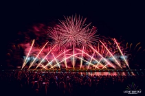 Auf dem Bild ist das Ostufer der Weserpromenade in Bodenwerder aus Sicht der gegenüberliegenden Seite in der Dunkelheit zu sehen. Am Ostufer ist ein Feuerwerk in verschiedenen Pinktönen zu sehen. Das verschiedene Feuerwerk geht gerade sowie schräg in die Luft. Oben Mittig zerspringt gerade ein Feuerwerkskörper, sodass ein pinker Feuerwerks-Ball zu sehen ist.&nbsp;&copy;&nbsp;Purple Box Production GmbH
