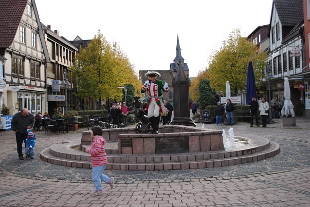 Musik am Brunnen findet jeden dritten Sonntag im Monat, in der Fußgängerzone, der Münchhausenstadt statt.
Auf dem Bild ist der Baron zu sehen, er trägt ein rot- grünes Gewandt mit einer weißen Hose, dazu trägt er hohe schwarze Schuhe, und auf den Kopf einen schwarzen Hut.
Er hält sein Mikrofon auf der Hand und steht dabei auf dem Brunnen des Stadtkerns.
Um ihn herum ist steht das Publikum.&nbsp;&copy;&nbsp;Samtgemeinde Bodenwerder-Polle