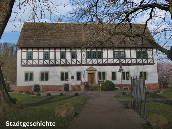 Stadtgeschichte.jpg Zu sehen ist das Geburtshaus des Baron von Münchhausen und heutiges Rathaus der Münchhausenstadt Bodenwerder sowie der Samtgemeinde Bodenwerder-Polle. Bauweise des oberen Stockwerks ist Fachwerkbauweise in weiß mit dunkelbraunen Balken. Das darunterliegende Stockwerk ist weiß gestrichen, mit einem rötlichen Sockel. Über dem Eingang, der mittig am Gebäude liegt, ist eine Inschrift zu sehen. Links von der Tür das Wappen der Münchhausenstadt. Zum Eingang führt eine Steintreppe hoch. Das Bild ist von einem gepflasterten Weg aufgenommen, der direkt auf das Rathaus und den Eingang zusteuert. Vor dem Gebäude ist ein rundlich gepflasterter Vorplatz, welcher von Kies und Buchsbäumen umgeben ist. © Samtgemeinde Bodenwerder-Polle/Rolf Sander