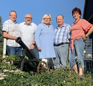 Auf dem Bild ist der Vorstand des Freundeskreis Münchhausen e.V., bestehend aus fünf Personen, zu sehen. Diese stehen nebeneinander hinter einem grünen Gewächs, in welchem eine kleine schwarze Kanonenkugel platziert ist. Von links nach rechts sind zu sehen, der Kassenführer Thomas Schädel, der auf einen Pfahl gelehnt steht und ein hell gemustertes Hemd zu einer Jeans und der Vorsitzende Herr Kühn, ebenfalls mit einem hell gemusterten Hemd zu einer Jeans. Daneben die Schriftführerin Frau Niegel mit einer blau gestreiften langen Bluse. Rechts davon der Beisitzer Herr Wedekind in einem gräulich karierten Hemd zu einer grauen Hose. Ganz rechts steht die stellvertretende Vorsitzende Una Seele in einer Jeans und einem rot gemusterten Oberteil.&nbsp;&copy;&nbsp;Freundeskreis Münchhausen e.V.